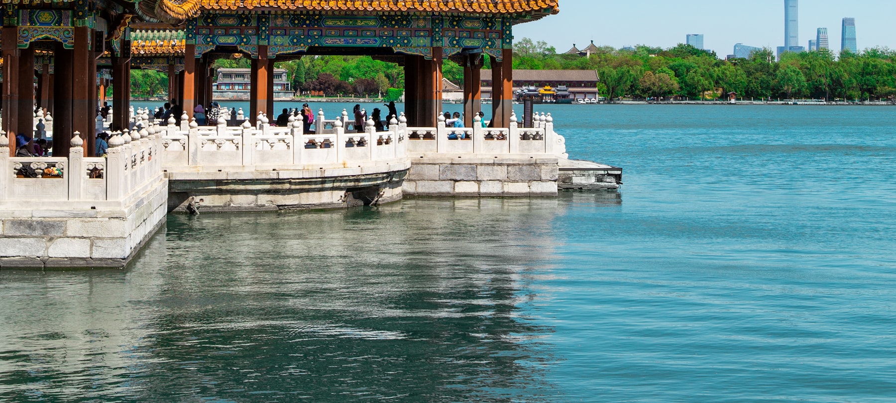 A lakeside pavilion in Beihai Park with the modern Beijing skyline beyond